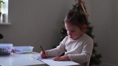 Süslü saçlı, çörek boyama kitabı olan küçük bir kız. Kötü duruş. Okul öncesi etkinlik, evde eğitim. Yaratıcı sanatçı