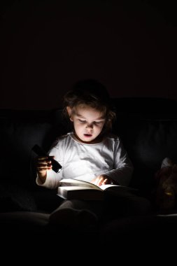 Akşamları elinde fenerle kitap okuyan beyaz bir kız. Fişi çekilmiş çocukluk aktiviteleri. İyi geceler uyku zamanı rutini. Fantezi masalı okumak