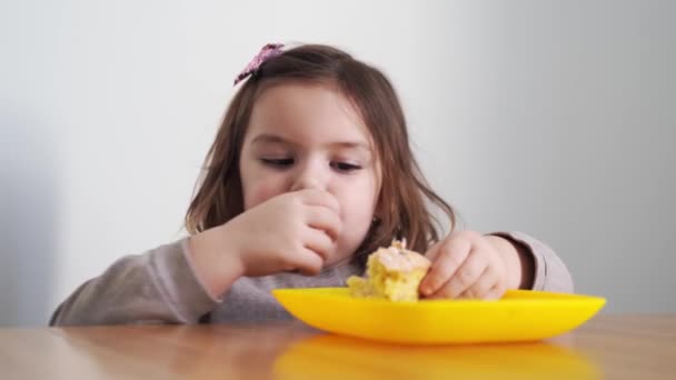 Kislány kenyeret vagy pitét eszik otthon a kezével. Éhes kölyök. Egészségtelen táplálkozás. Rossz étkezési szokások — Stock videók