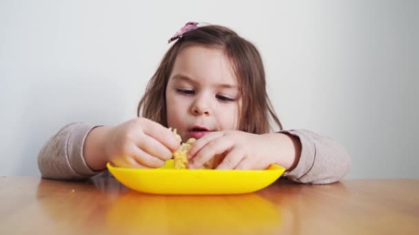 Menina da criança comendo pão ou torta em casa com as mãos. Miúdo faminto. Dieta pouco saudável. Maus modos de mesa — Vídeo de Stock