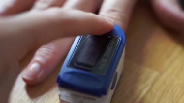 Parmak üzerinde nabız oksimetresi olan bir kadın. Zatürree covid semptomu. Kan oksijen seviyesi.