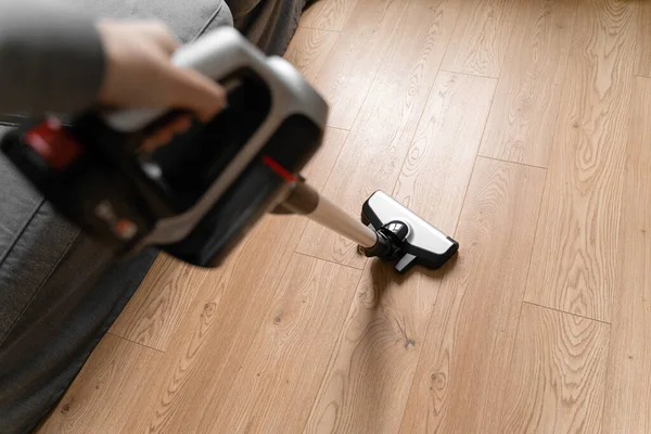 Cleaning wooden floor with wireless vacuum cleaner. Handheld cordless cleaner. Household appliance. Housework modern equipment — Stock Photo, Image