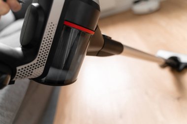 Kablosuz elektrik süpürgesiyle ahşap zemini temizliyorum. El bilgisayarı kablosuz temizleyici. Ev aletleri. Ev işi modern ekipmanlar