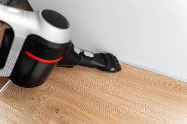 Kablosuz elektrik süpürgesiyle ahşap zemini temizliyorum. El bilgisayarı kablosuz temizleyici. Ev aletleri. Ev işi modern ekipmanlar
