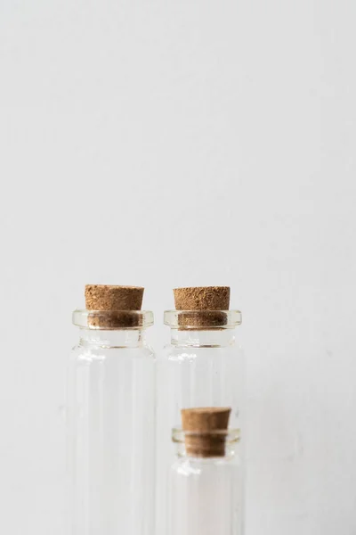 Trois bouteilles en verre avec bouchon en liège sur podium en bois avec fond mural blanc. Remplissage huile essentielle magasin. Modèle de maquette. — Photo