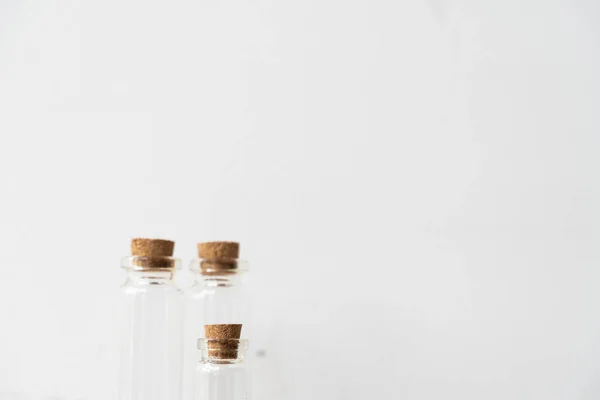 Trois bouteilles en verre avec bouchon en liège sur podium en bois avec fond mural blanc. Remplissage huile essentielle magasin. Modèle de maquette. — Photo