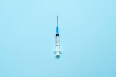 Mavi arka planda enjeksiyon şırıngasının üst görüntüsü. Asgari aşı konsepti. Diyabetin ensülin ile tedavi edilmesi. Covid-19 aşısı. Antivax kampanyası 