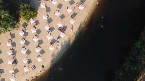 Vista aerea dall'alto sulla spiaggia di sabbia del fiume con lettini e ombrelloni. Concetto di viaggio locale. Stile di vita sostenibile, riduzione dell'impronta ecologica. Drone vista del resort lungo il fiume — Video Stock