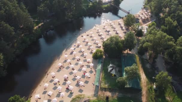 Aerial top udsigt over floden sandstrand med lounger og paraplyer. Lokalt rejsekoncept. Bæredygtig livsstil, reducere carbon footprint. Drone udsigt over floden udvej – Stock-video