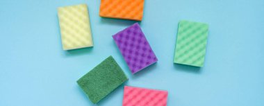 Mavi arka planda temiz renkli süngerler. Üst görünüm minimal stil. Bahar temizliği konsepti. Bulaşıklar için ev aletleri.