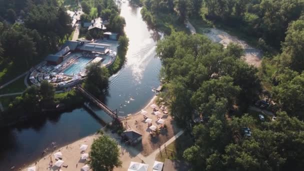 Aerial top view of river sand beach with hotel cabins and pool. Local travel concept. Sustainable lifestyle, reducing carbon footprint. Drone view of riverside resort — Stock Video