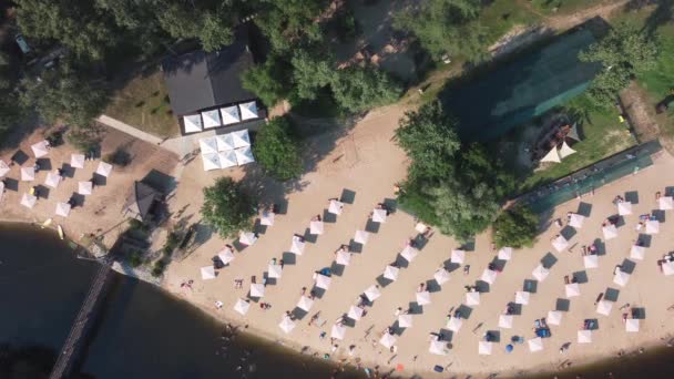 Aerial top view of river sand beach with lounges and umbrellas. Local travel concept. Sustainable lifestyle, reducing carbon footprint. Drone view of riverside resort — Stock Video