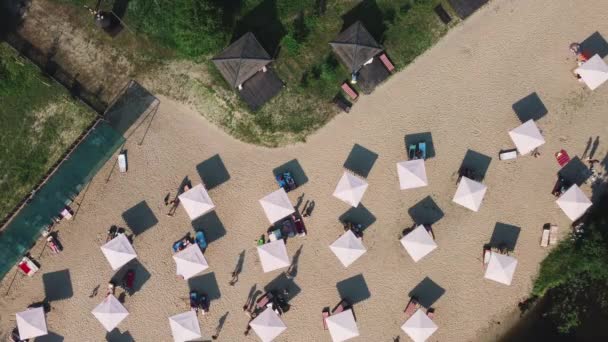 Vista aerea dall'alto sulla spiaggia di sabbia del fiume con lettini e ombrelloni. Concetto di viaggio locale. Stile di vita sostenibile, riduzione dell'impronta ecologica. Drone vista del resort lungo il fiume — Video Stock