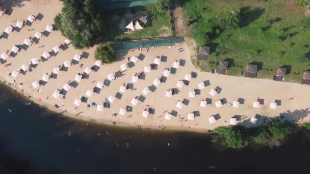 Vista aerea dall'alto sulla spiaggia di sabbia del fiume con lettini e ombrelloni. Concetto di viaggio locale. Stile di vita sostenibile, riduzione dell'impronta ecologica. Drone vista del resort lungo il fiume — Video Stock