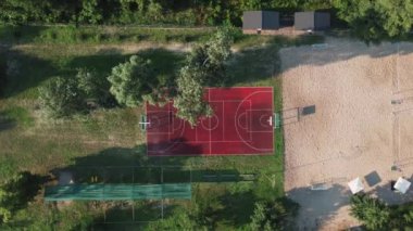 Doğa ortamında basketbol sahasının havadan görünüşü. Günbatımı yaz tatili eğlence cemiyeti bölümünde. Kentsel sporların İHA videosu.