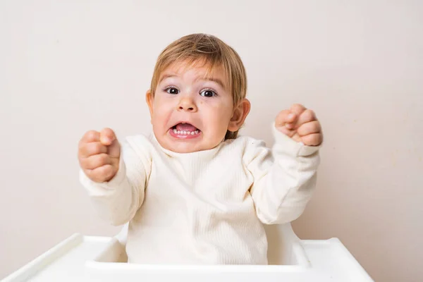 Kleinkind Baby sitzt auf dem Hochstuhl und macht lustige Fratzen. Die Zähne des Babys. Gesichtsausdruck — Stockfoto