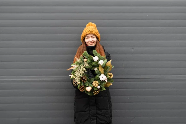 Young woman with Christmas wreath on grey wall background. Copy space Christmas banner. Handmade eco decoration for winter holidays — Stock Photo, Image