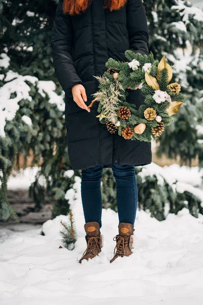 Mujer joven con corona de Navidad en invierno día nevado. Copiar espacio Banner de Navidad. Decoración ecológica hecha a mano para vacaciones de invierno — Foto de Stock