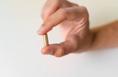 Beyaz arka planda bitki kapsülüyle elinizi kapatın. Mikrodoz konsepti. Psikedelik terapisi. Depresyon, endişe tedavisi 