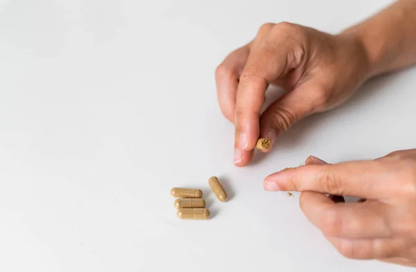 Beyaz arka planda bitki kapsülüyle elinizi kapatın. Mikrodoz konsepti. Psikedelik terapisi. Depresyon, endişe tedavisi 