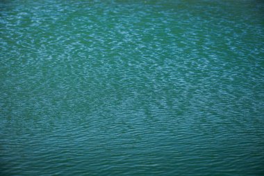 Rüzgâr gölü, açık mavi rengin yüzeyinde güneşli bir yaz gününde doğa üzerindeki berrak mavi su dokusunda izler bırakır.