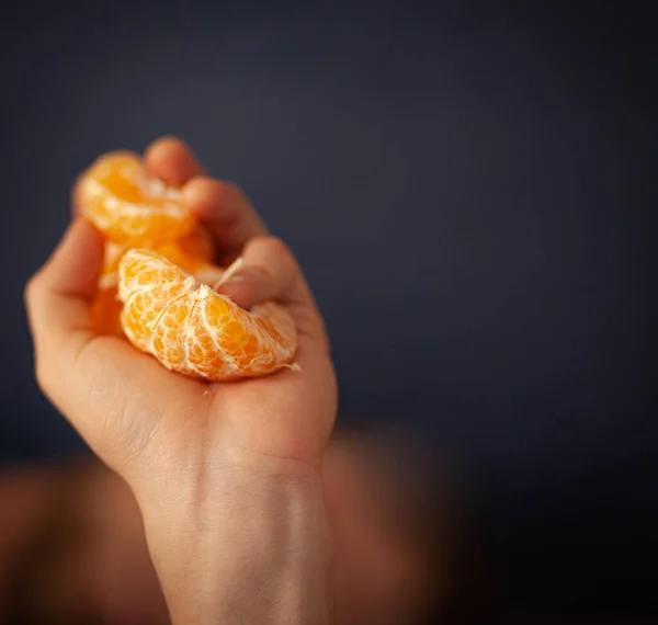 juicy orange citrus peeled fruit lies in hand on gray-blue background