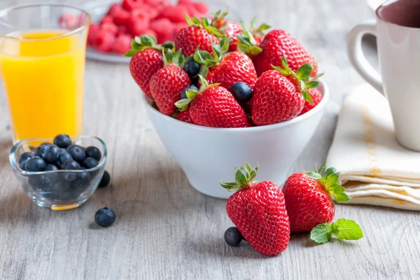 Aardbeien op houten tafel met dagelijks ontbijt — Stockfoto