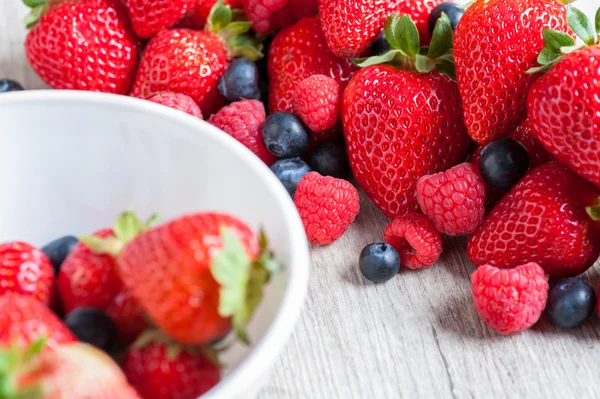 Fresas, bayas y frambuesas sobre mesa rústica de madera —  Fotos de Stock