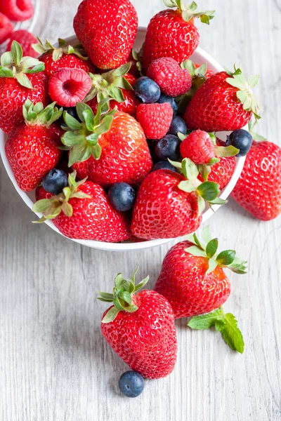 Fresas, bayas y frambuesas sobre mesa rústica de madera —  Fotos de Stock