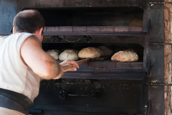 Introducing artisan baker dough in the oven — Stock Photo, Image
