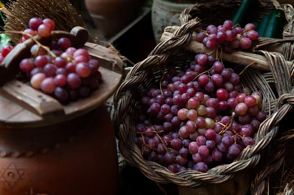 Various bunches of red grapes on wicker basket — Stock Photo, Image