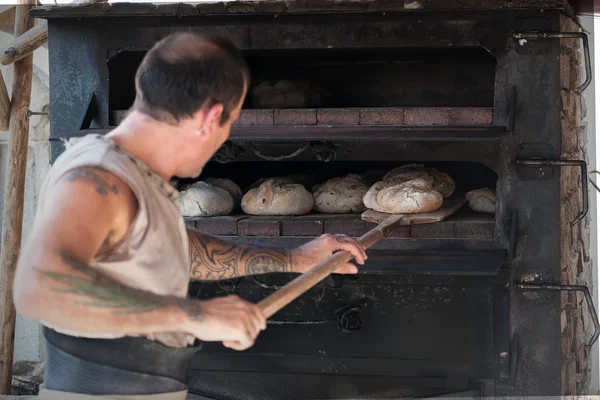 Introducing artisan baker dough in the oven — Stock Photo, Image