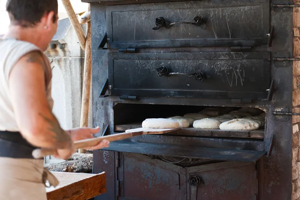 Introducing artisan baker dough in the oven — Stock Photo, Image