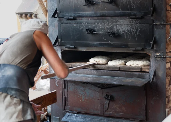 Bäcker stellt das Produkt im Holzofen vor — Stockfoto