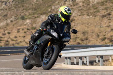 Ön planda yol bisikleti, asfaltta sürüyor ve virajda yatıyor. Fotoğraf Eylül 202 'de İspanya' nın Avila ilinde çekildi.