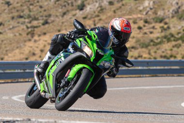 Ön planda yol bisikleti, asfaltta sürüyor ve virajda yatıyor. Fotoğraf Eylül 202 'de İspanya' nın Avila ilinde çekildi.