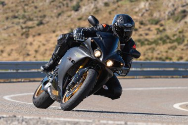 Ön planda yol bisikleti, asfaltta sürüyor ve virajda yatıyor. Fotoğraf Eylül 202 'de İspanya' nın Avila ilinde çekildi.