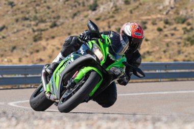 Ön planda yol bisikleti, asfaltta sürüyor ve virajda yatıyor. Fotoğraf Eylül 202 'de İspanya' nın Avila ilinde çekildi.