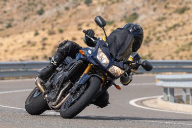 Asfalt üzerinde dolaşan motosikletçi; Eylül 2020 'de İspanya' nın Avila ilinde yakalanan fotoğraf