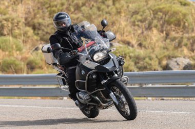 Asfalt üzerinde dolaşan motosikletçi; Eylül 2020 'de İspanya' nın Avila ilinde yakalanan fotoğraf