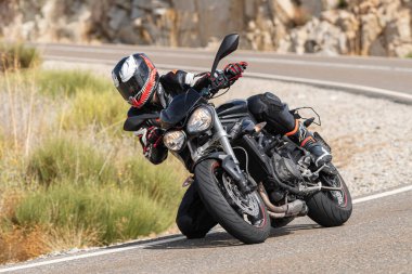Asfalt üzerinde dolaşan motosikletçi; Eylül 2020 'de İspanya' nın Avila ilinde yakalanan fotoğraf