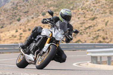 Genç adam yolda motosikletini sürüyor. Fotoğraf Eylül 2020 'de Navalmoral, Avila, İspanya Limanı' nda çekildi.