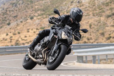 Genç adam yolda motosikletini sürüyor. Fotoğraf Eylül 2020 'de Navalmoral, Avila, İspanya Limanı' nda çekildi.