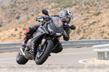 Genç adam yolda motosikletini sürüyor. Fotoğraf Eylül 2020 'de Navalmoral, Avila, İspanya Limanı' nda çekildi.