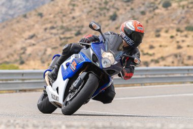 Genç adam yolda motosikletini sürüyor. Fotoğraf Eylül 2020 'de Navalmoral, Avila, İspanya Limanı' nda çekildi.