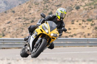 Genç adam yolda motosikletini sürüyor. Fotoğraf Eylül 2020 'de Navalmoral, Avila, İspanya Limanı' nda çekildi.