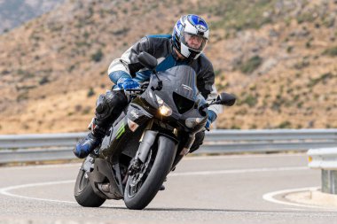 Genç adam yolda motosikletini sürüyor. Fotoğraf Eylül 2020 'de Navalmoral, Avila, İspanya Limanı' nda çekildi.