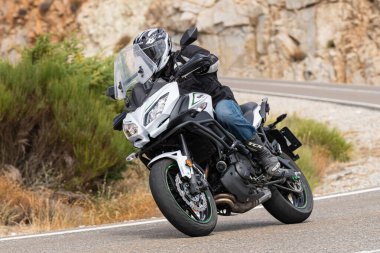 Genç adam yolda motosikletini sürüyor. Fotoğraf Eylül 2020 'de Navalmoral, Avila, İspanya Limanı' nda çekildi.