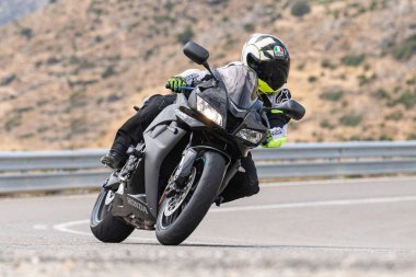 Genç adam yolda motosikletini sürüyor. Fotoğraf Eylül 2020 'de Navalmoral, Avila, İspanya Limanı' nda çekildi.