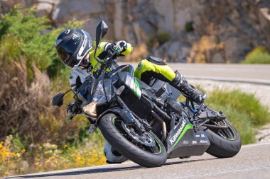 Motosikletli bir sürücü keskin bir viraj yapıyor. Fotoğraf 4 Temmuz 2021 'de Avila, Spai' deki Navalmoral limanında çekildi.